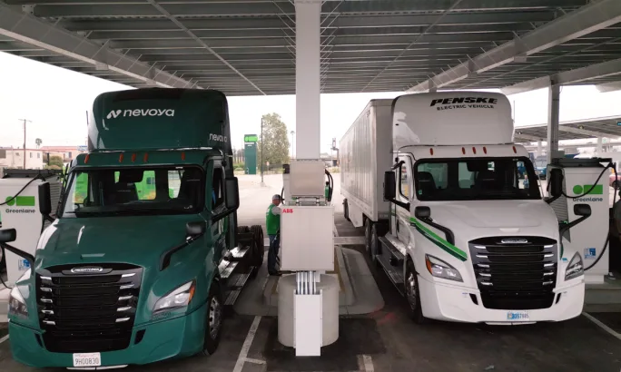 Greenlane charging station with Nevoya and Penske electric trucks connected to chargers under a solar canopy.