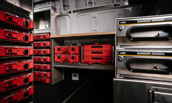 Inside view of a work van equipped with Ranger Design storage units holding Milwaukee Packout toolboxes and organizers.
