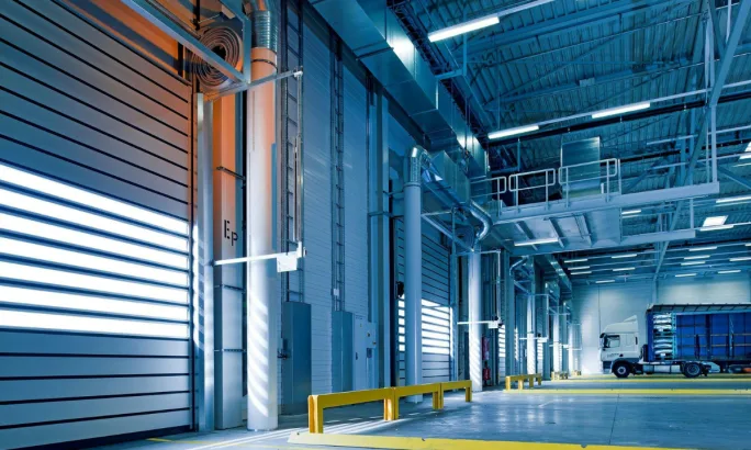 Interior of a large, modern fleet maintenance facility with truck bays and overhead lighting, illustrating the type of building that may require retrofitting.