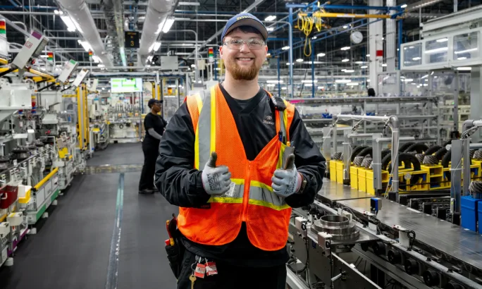 Toyota Alabama employee smiling in safety vest on differential production floor in Huntsville.