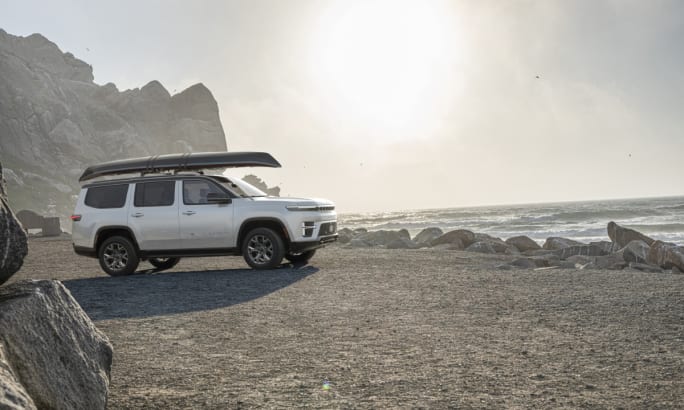 White 2026 Jeep Grand Wagoneer parked by the beach with a canoe mounted on the roof.