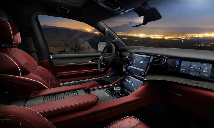 Interior view of the 2026 Jeep Grand Wagoneer featuring red leather seats, dual screens, and panoramic views.