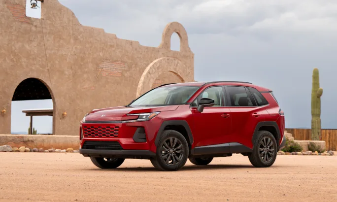 Red 2026 Toyota RAV4 Woodland grade SUV parked on a desert backdrop near adobe architecture and cacti.