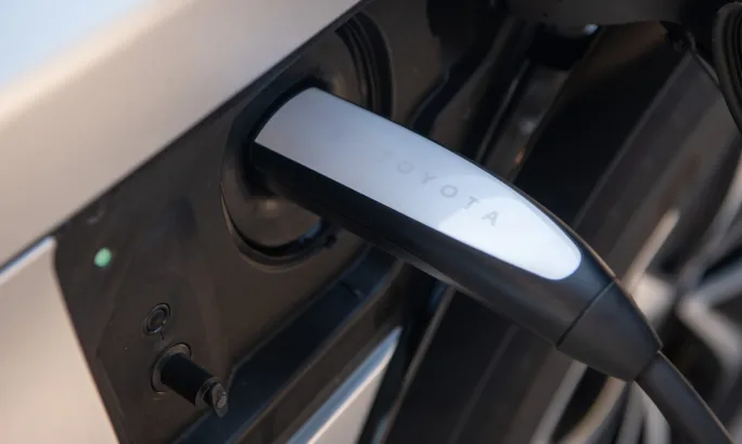 Close-up view of a Toyota electric vehicle charging port with a NACS connector plugged in.