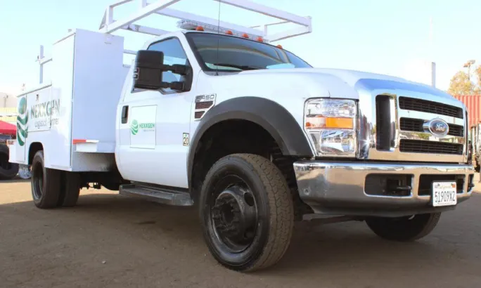 Front quarter low angle view of a white service truck parked.