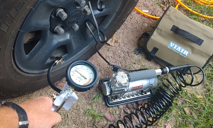 Closeup of man using a portable air compressor to inflate a tire.