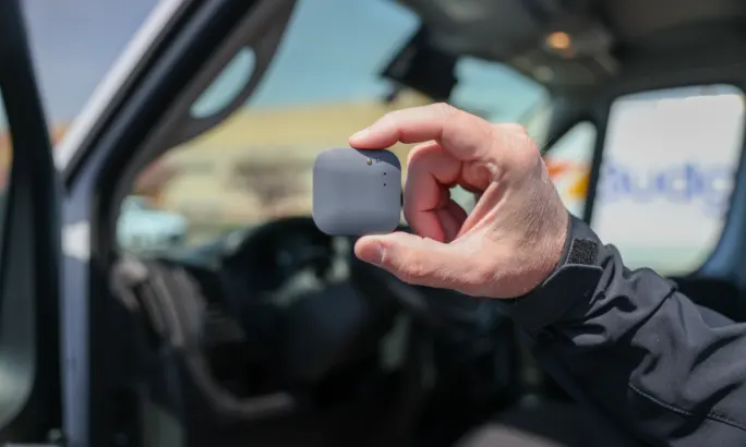 Hand holding a Tag Max device from DriveWell