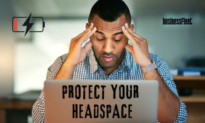 A small fleet manager sits at a laptop holding his head, representing the mental load of managing operations, drivers, maintenance, and decisions while working to reduce stress and protect focus.