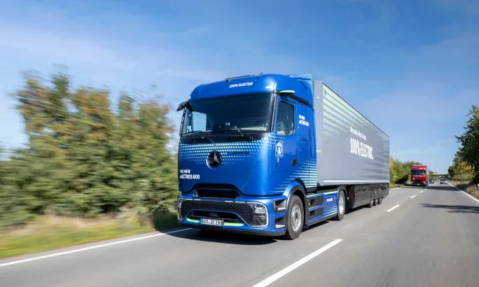 Blue Mercedes-Benz eActros 600 electric semi-truck driving on a highway.