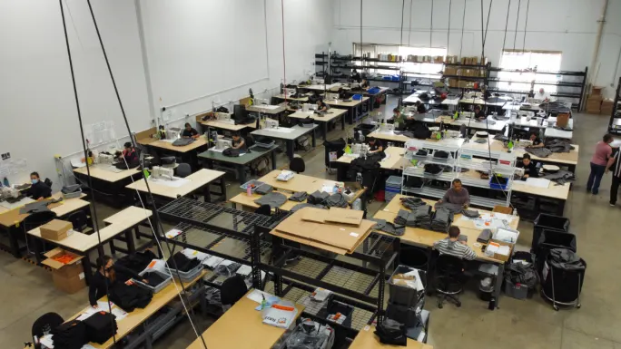 Employees sewing and assembling seat covers inside Tiger Tough’s U.S.-based manufacturing facility with worktables and materials visible.