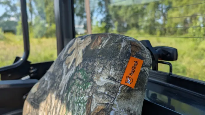 Close-up of a camouflage Tiger Tough seat cover installed in a utility vehicle, showing rugged fabric and branded tag.