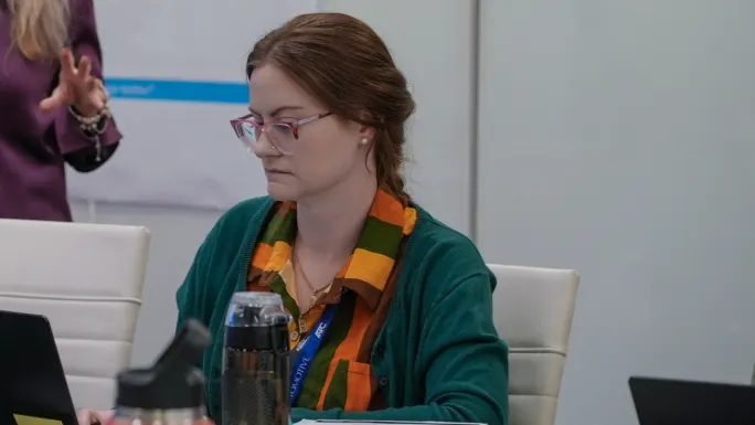 Mikhaila Baldwin working on a laptop in a meeting, reviewing data with a colleague nearby, representing fleet management and operational decision-making.