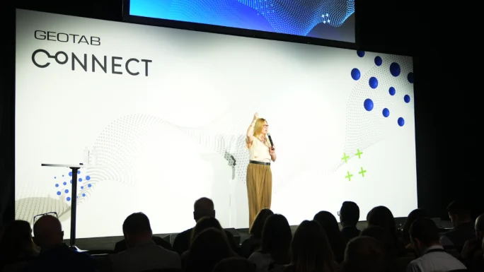 Lori Olson presenting on stage at Geotab Connect conference to an audience, discussing fleet technology and industry collaboration.