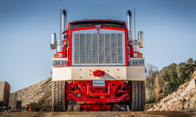 Low-angle front view of a red Kenworth truck with a chrome grille.