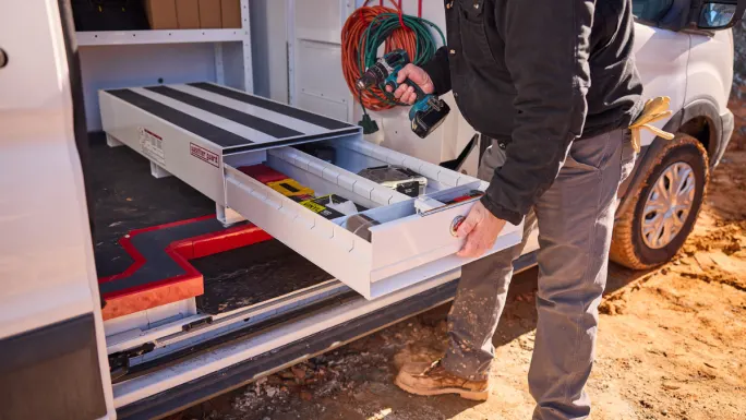 Technician accessing organized slide-out drawer system inside service van with tools stored for easy reach.