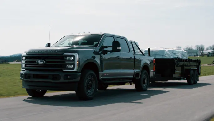2027 Ford Super Duty pickup towing a trailer on a rural road during daylight.