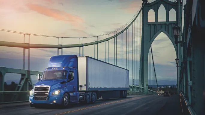 A blue Freightliner truck crossing an Oregon bridge