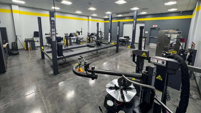 Bright BendPak training showroom featuring vehicle lifts, tire changers, wheel balancers, and alignment equipment in a clean, modern workspace designed for hands-on automotive service training and product demonstrations.