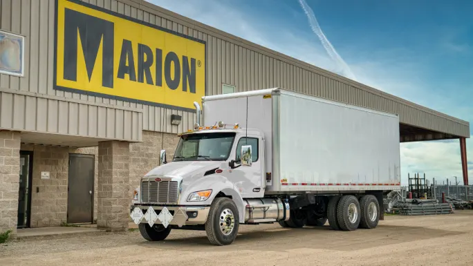 White commercial truck equipped with an enclosed Marion dry van body parked outside the Marion Body Works facility.