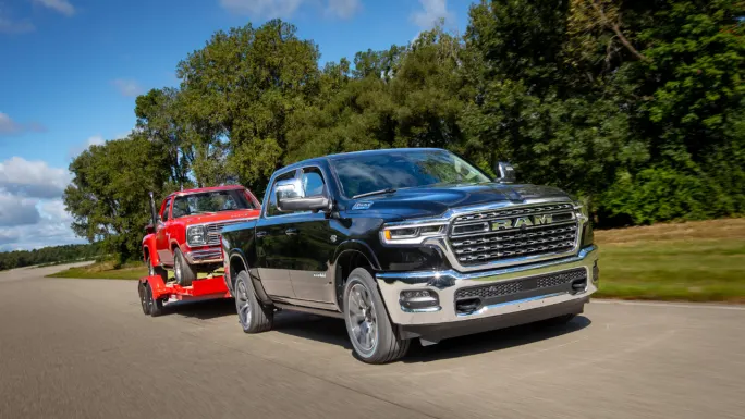 2026 Ram 1500 Limited with 5.7L HEMI V8 eTorque towing a red 1978 Dodge Li’l Red Express pickup on a trailer.