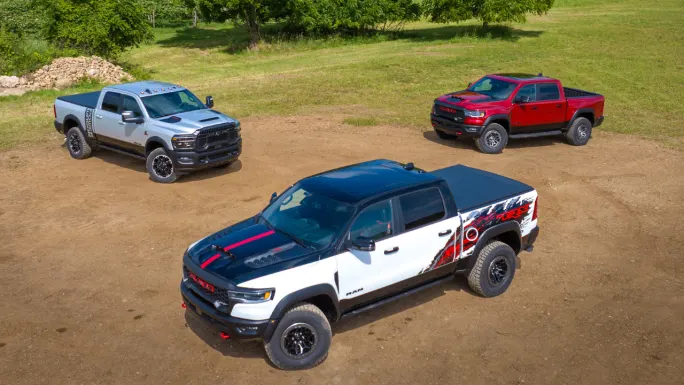 Three Ram trucks parked on a dirt field, including a 2027 Ram 1500 TRX SRT and 2027 Ram 2500 Power Wagon with Cummins turbo-diesel power.