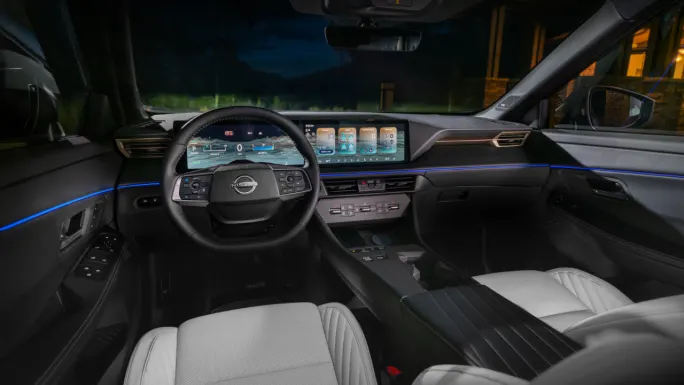 Interior of the 2027 Nissan Rogue Hybrid showing the steering wheel, digital instrument display, center touchscreen, climate controls, and front seating.
