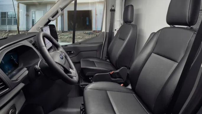 Interior of a Ford Transit Cargo Van showing the driver and passenger seats, steering wheel, digital instrument display, and center touchscreen.