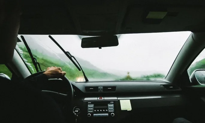 A pair of hands changing the windshield wipers on a car.