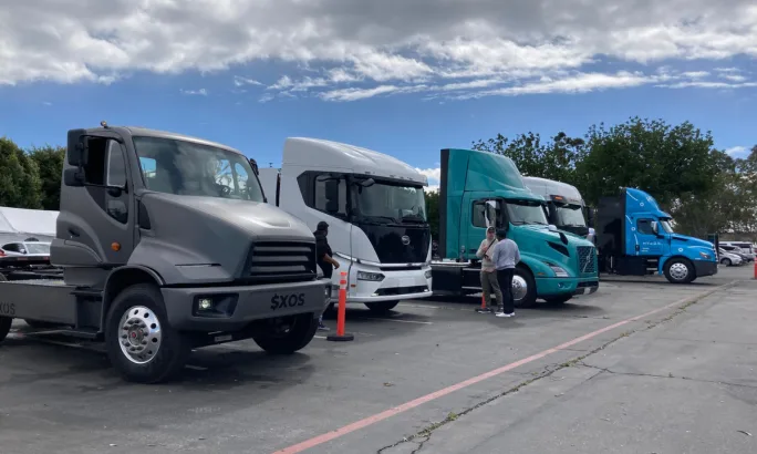 Electric trucks lined up in parking lot.