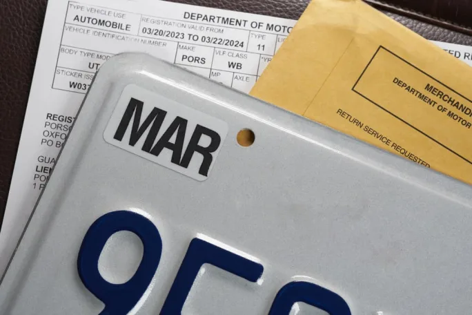 Close-up of a vehicle license plate with registration documents and DMV paperwork