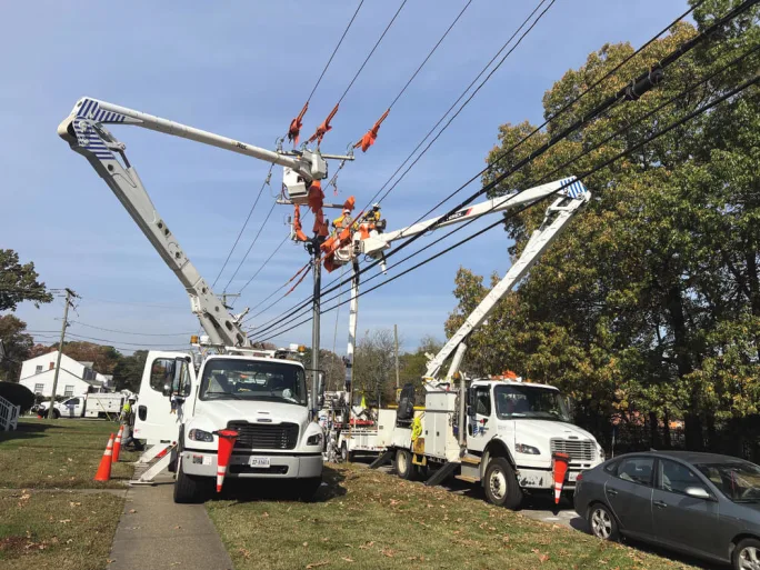 Utility crews working from boom trucks to repair storm-damaged power lines illustrating the role of service vehicles and coordinated recovery during disaster response operations.