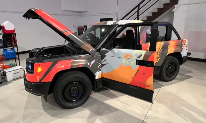 A Slate SUV wrapped in bright color patters on display with all doors and lids open.