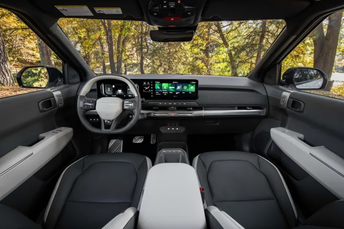Interior of Kia EV3 showing digital dashboard, steering wheel, center touchscreen, and minimalist cabin design with modern controls.