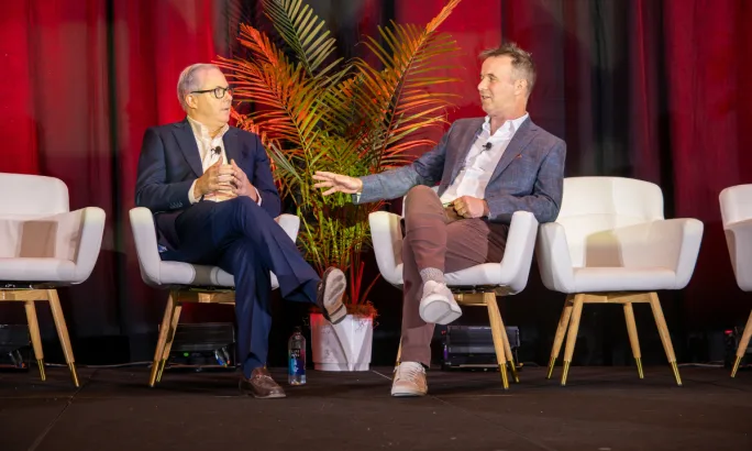 ACRA President Don Lefeve and Chairman Sharky Laguna seated in white chairs on a conference stage accented with a dark red background curtain.
