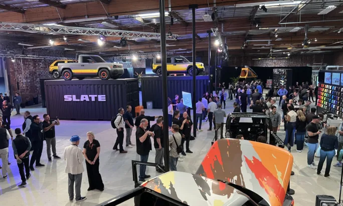 Overview of guests mingling on a warehouse floor made over into an elegant vehicle debut event.
