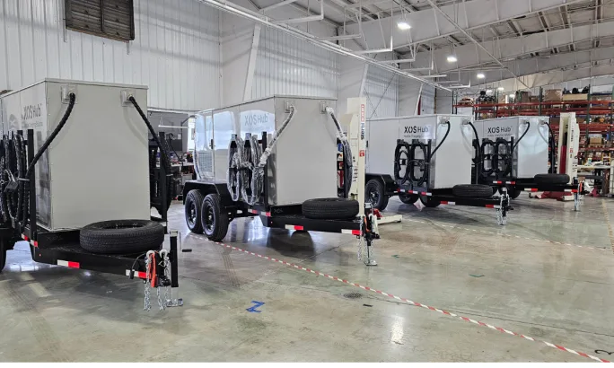 A row of box white trailer charging and battery storage hubs.