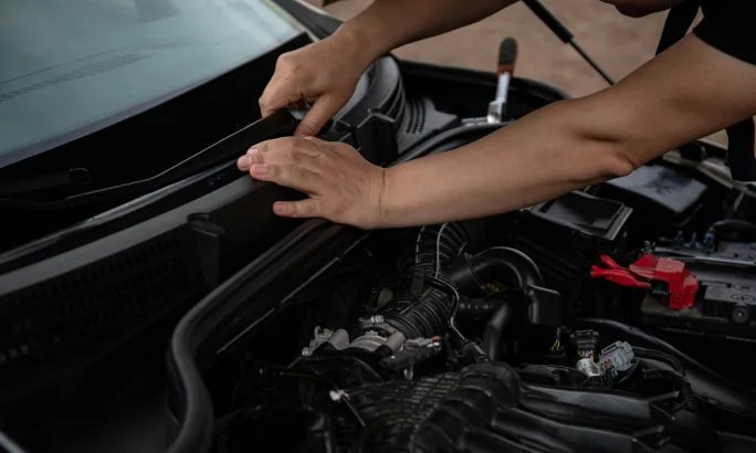 Someone checking front windshield wipers as they check under the hood.