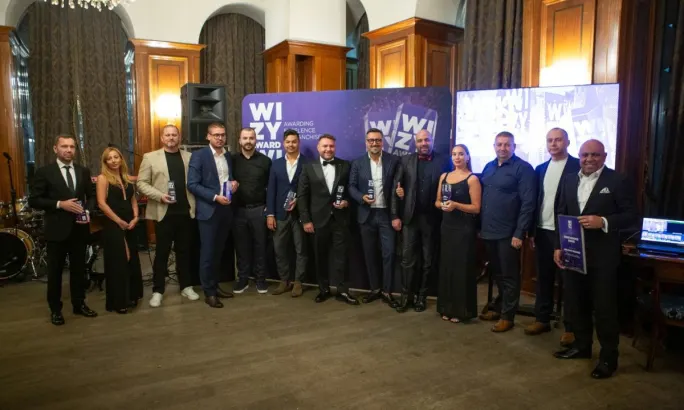 Award winners lined up in a ballroom holding their award memorabilia.