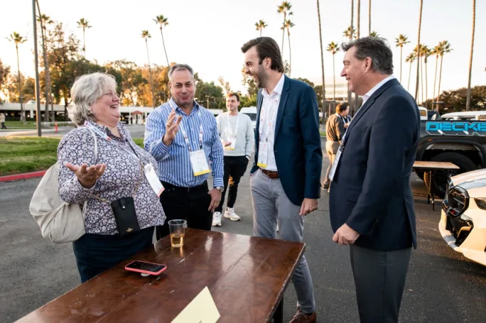 Four event attendees chat near ride and drive vehicles.