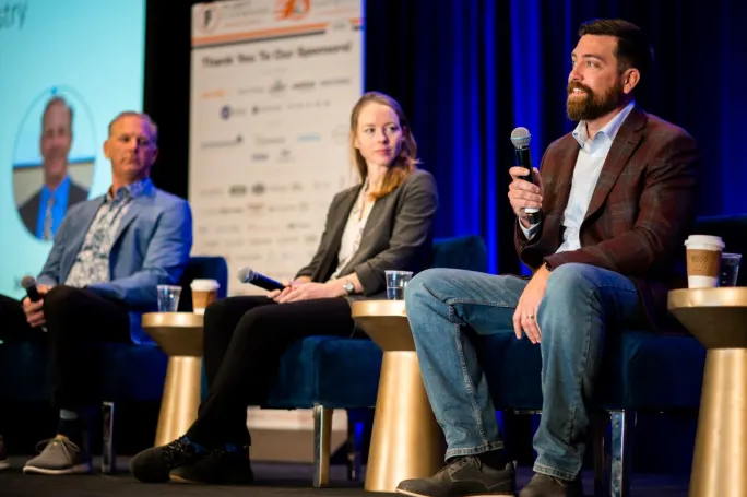 Three people on stage delivering a seminar.