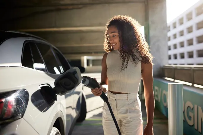 A Gen Z car renter uses an EV charger on her rental car.