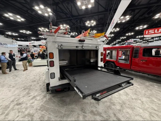Rear view of Morgan Olson Kestrel work truck with BedSlide cargo tray extended from service body, showing organized storage and slide-out work surface at Work Truck Week.