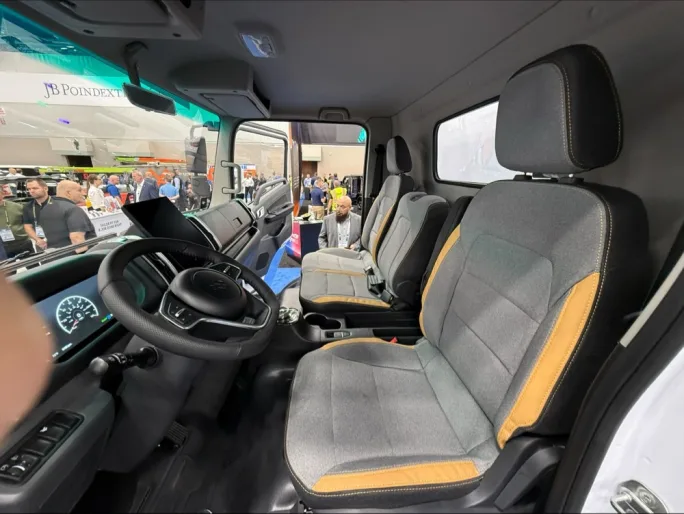 Interior of Harbinger HC Series Cab work truck showing steering wheel, digital gauges, center display, and three-seat cab layout on the Work Truck Week show floor.