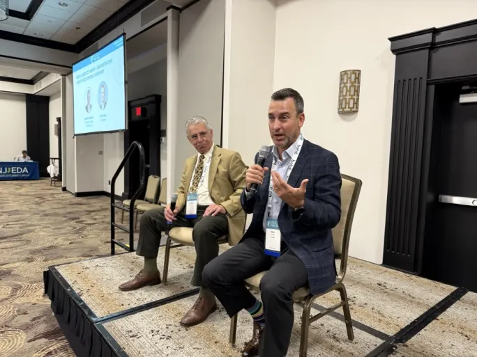 Robert Martines and Trip O'Neil sit on a stage holding microphones as they host a panel at the NJ Tour Stop.