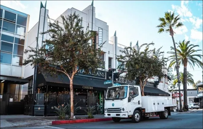 A Mullen Automotive truck outside businesses.
