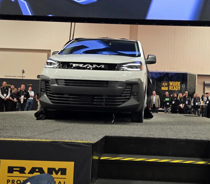 Front view of the 2027 Ram ProMaster City displayed on a stage during its unveiling at Work Truck Week, with attendees gathered around the platform.