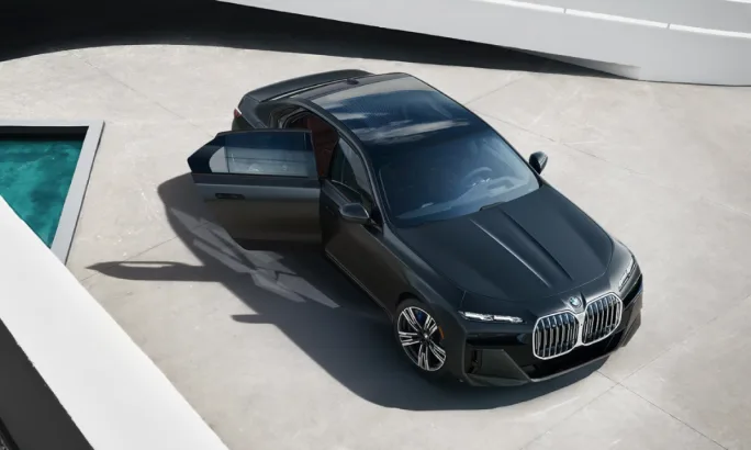 An overhead view of a black 2025 BMW 7 Series vehicle on gray pavement.