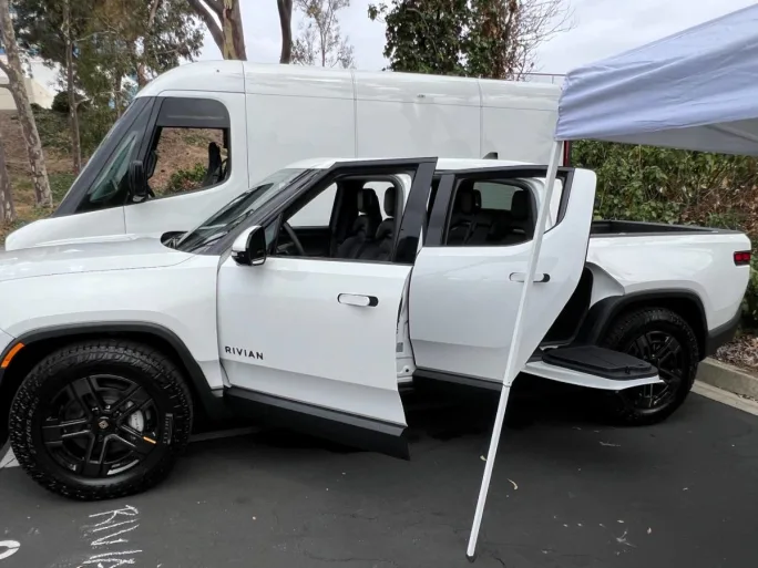 A white four-door Rivian all-electric pickup truck.