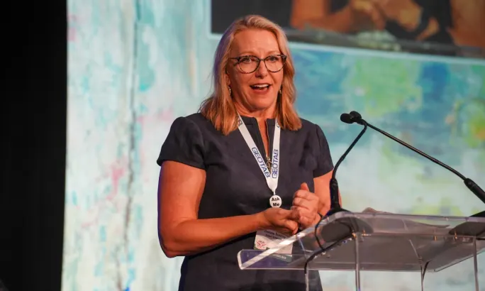 Theresa Belding on stage speaking at a podium.