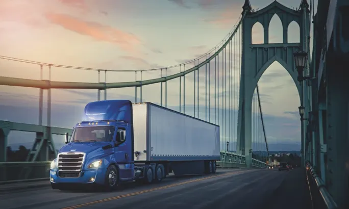 A blue day cab semi driving across a suspended bridge in Oregon.